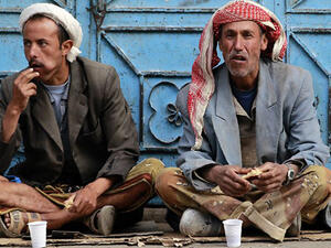 Unemployed Yemeni manual laborers eat as they wait for work offers on a sidewalk in Sanaa. (AFP/File)