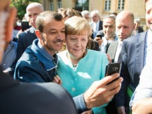 مهاجر يلتقط صورة سيلفي مع المستشارة الالمانية انغيلا ميركل
