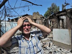 An Ethnik Uzbek holds his head in his hands as he stands beside the wreckage of his burned out home in Osh on June 14, 2010