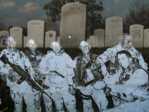 Headstones are reflected in a photograph that is leaning against the headstone for Iraq war casualty U.S. Army Master Sgt. Tulsa Tulaga Tuliau on the 10th anniversary of the beginning of the war in Iraq. (Getty Images/AFP)