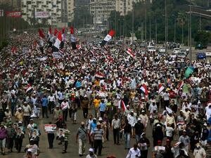 EGYPT, Cairo : Supporters of the Muslim Brotherhood and ousted Egyptian president Mohamed Morsi raise pictures of the toppled leader and wave the national flag during a demonstration in Cairo, on July 19, 2013. (AFP PHOTO /MARWAN NAAMANI)
