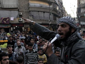A member of the Islamic State of Iraq and the Levant (ISIL) speaks into a microphone urging people to join their fight against the regime, in the northern Syrian city of Aleppo on November 13, 2013. [Getty Images]