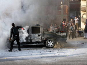 An Egyptian policeman tries to extinguish a police vehicle set on fire by Muslim Brotherhood supporters on a ring road in the capital, Cairo, on January 3, 2014. [Getty Images]