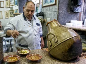 Just about everything at Hashem Restaurant exudes the grittiness of this city's rough-and-tumble downtown: chefs in white aprons
scoop fuul (fava beans) out of vase-shaped metal jars and plop it on to plastic bowls.