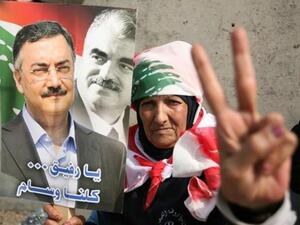 One of the mourners holds a picture of Hassan (left) with Rafiq Hariri (right): (picture courtesy of Hasan Shaaban/Daily Star) One of the mourners holds a picture of Hassan (left) with Rafiq Hariri (right): (picture courtesy of Hasan Shaaban/Daily Star)