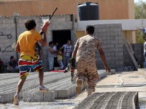 Members of Libyan security forces run away holding weapons during clashes between protesters and troops of the Libyan Shield Forces (LSF), a coalition of militias, in Benghazi. AFP Photo
