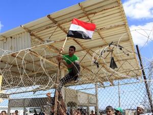 A Palestinian protestor puts up an Egyptian flag on barbed wire during a rally in front of the Rafah border crossing in the southern Gaza Strip on September 16, 2013. (AFP)