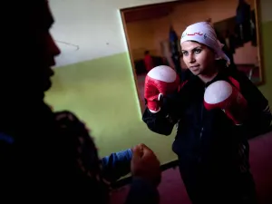 An Afghani woman in a head scarf playing boxing.