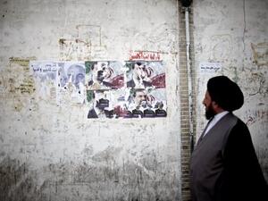 An Iranian clergyman walks past electoral posters of presidential candidates in Qom, south of Tehran, ahead of Friday's elections. AFP image