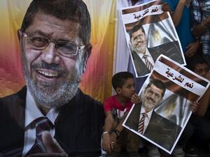 Supporters of deposed Egyptian president Mohamed Morsi (portrait) watch a football match between the two main Cairo protest camps by members of the Muslim Brotherhood and backers of the ousted Islamist leader set up at the Nahda and Rabaa al-Adawiya squares, on August 11, 2013 in Cairo's al-Nahda square/ (AFP)