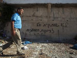 A Palestinian man was past graffiti that reads in Hebrew, "'We do not remain silent in face of stone throwing" as he walks past a wall in the Arab east Jerusalem neighborhood of Beit Hanina, on Monday. (AFP)