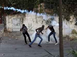 A Palestinian protester hurls a smoke grenade back at Israeli soldiers during clashes in Betunia near the West Bank city of Ramallah on September 20, 2013 (AFP)