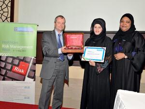 Dr. Moza Alishaq hands over a memento of appreciation to Gary Needle in the presence of Dr. Badriya Al Ali