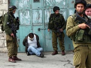 جنود اسرائيليون يحيطيون بفلسطيني معتقل ومعصوب العينين خلال عملية في الضفة الغربية 
