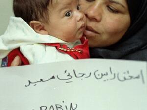 Jordanian infant Yitzhak Rabin and his mother Miriam hold a paper with his name at their home in Jordan, in March 1996, shortly after the government permitted the boy to carry the name of the slain Israeli prime minister. [Al-Arabiya]