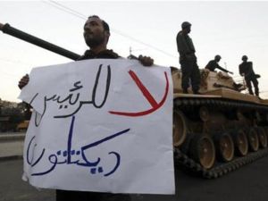 متظاهر مناهض لمرسي يحمل لافتة ويقف امام دبابة امام قصر الرئاسة في القاهرة