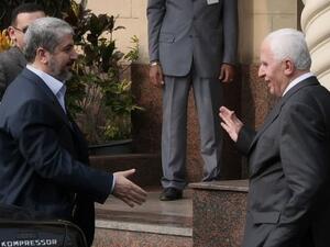 القيادي في فتح عزام الاحمد (يمين) مصافحا القيادي في حماس خالد مشعل في القاهرة
