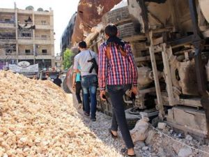 مقاتلون من الجيش السوري الحر يحملون أسلحة وهم يمرون وسط حواجز للحماية من قناصة قوات الأسد في حي سيف الدولة بحلب