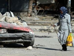 امراة تمر من امام حطام سيارة في حلب
