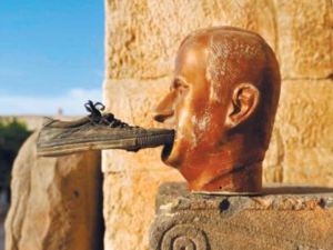 تمثال للرئيس السوري الراحل حافظ الاسد وقد دس احدهم حذاء في فمه