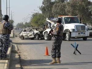 الشرطة العراقية تراقب عملية ازالة هيكل سيارة دمرت في تفجير انتحاري في بغداد الاسبوع الماضي
