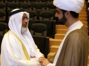 رئيس مجلس النواب البحريني خليفة الظهراني (يسار) مصافحا رجل دين شيعي في افتتاح الحوار 
