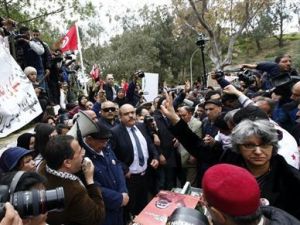 بسمة ارملة بلعيد تلوح بعلامة النصر مع مجموعة من اقارب زوجها الراحل امام قبره 
