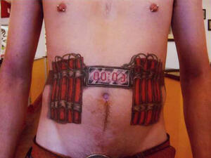 A man gets a tattoo of bombs strapped to his stomach. 