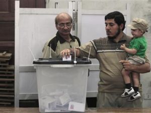 رجل يحمل طفلا ويدلي بصوته في مركز للاقتراع في القاهرة.