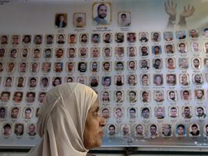 فلسطينية امام لافتة تحمل صور واسماء السجناء الفلسطينيين في السجون الاسرائيلية امام مبنى الصليب الاحمر في القدس الشرقية
