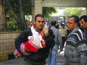 رجل يحمل طفلا اصيب في الانفجار الذي وقع عند مدخل مبنى المؤسسة العامة للخط الحديدي