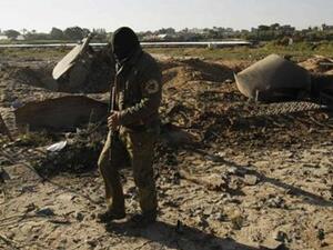 نشط فلسطيني ملثم يتفقد الاضرار التي لحقت بمعسكر تدريب بعد ضربة اسرائيلية على غزة يوم الخميس
