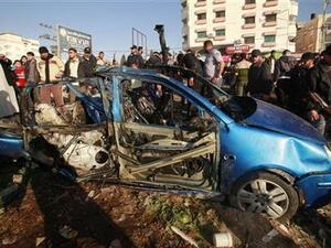 فلسطينون بجوار السيارة التي استهدفتها اسرائيل في مدينة غزة يوم الجمعة
