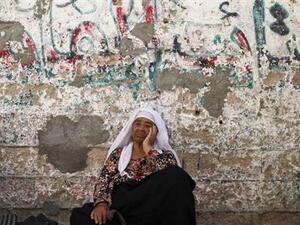 امرأة فلسطينية تجلس على الارض أمام منزلها في خان يونس بقطاع غزة
