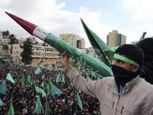 شاب فلسطيني يرفع نموذجا لصاروخ تصنعه حركة حماس خلال المسيرة في الخليل
