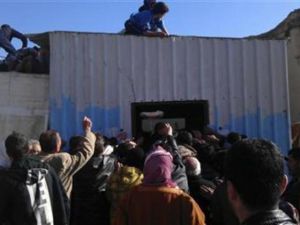 عناصر من الجيش الحر يحاولون تنظيم الدور امام مخبز في ادلب