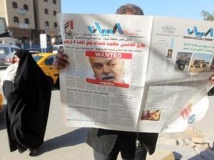 عراقي يقرأ صحيفة تصدرت صفحتها الاولى قصة امر اعتقال الهاشمي