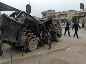 رجال عراقيون يسيرون الى جانب حافلة دمرها تفجير سيارة مفخخة في مدينة الصدر في بغداد
