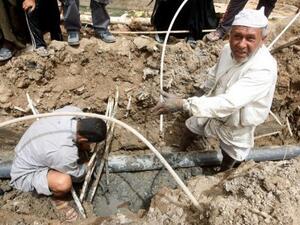 عراقيان يحاولان اصلاح انابيب المياه في الحي الذي يقيمان فيه في بغداد 
