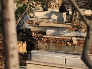 امرأة فلسطينية تجلس عن قبور اقاربها في مقبرة في مدينة رام الله في الضفة الغربية في اول ايام عيد الاضحى
