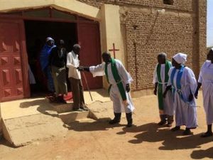 قس يساعد عجوزا بعد حضوره الصلاة في كنيسة على مشارف الخرطوم
