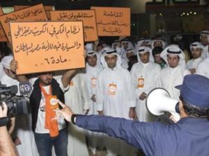 ضابط شرطة يتحدث في مكبر صوت لمحتجين في منطقة الشويخ بالعاصمة الكويت 
