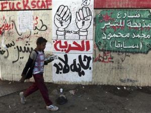 صبي يمر أمام رسوم وكتابة على حائط في القاهرة تنتقد المشير والمجلس العسكري 