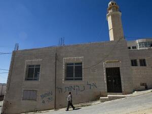 فلسطيني يمر امام مسجد كتبت عليه باليهودية عبارات مسيئة للنبي في بيت اكسا بالضفة الغربية
