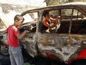 طفلان فلسطينيان يتفقدان سيارة والديهما المحروقة في نابلس