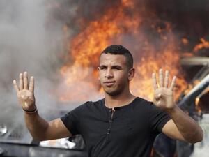 طالب من انصار مرسي يقف امام عربة محترقة للشرطة في ميدان النهضة في القاهرة
