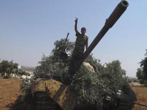 مقاتل من الجيش الحر يعتلي دبابة للجيش السوري غنمتها المعارضة المسلحة شمال حلب