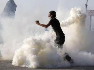 متظاهر يحمل قنبلة مسيلة للدموع ويستعد للالقائها باتحاه الشرطة