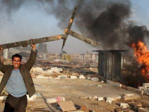 رجل يحمل قطعة خشب مكسورة من مخيم للاجئين السوريين احرقه السكان المحليون في شرق لبنان
