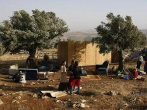 مستوطنون يقفون الى جانب كوخ من الخشب اعيد بناؤه في مستوطنة ميغرون العشوائية في الضفة الغربية 
